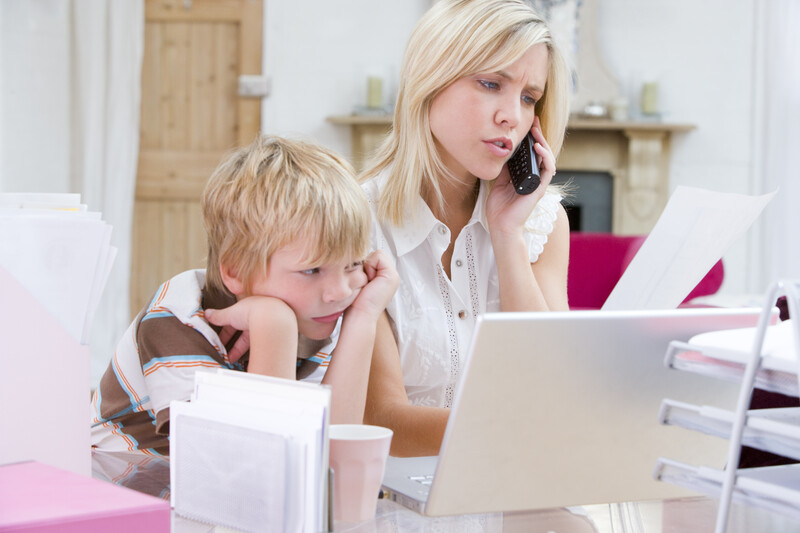Abstand gewinnen - junge Frau die im Büro mit Laptop telefoniert, während der Junge sich langweilt